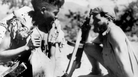 An East Timorese boy carrying supplies accompanying an Australian solider during World War II